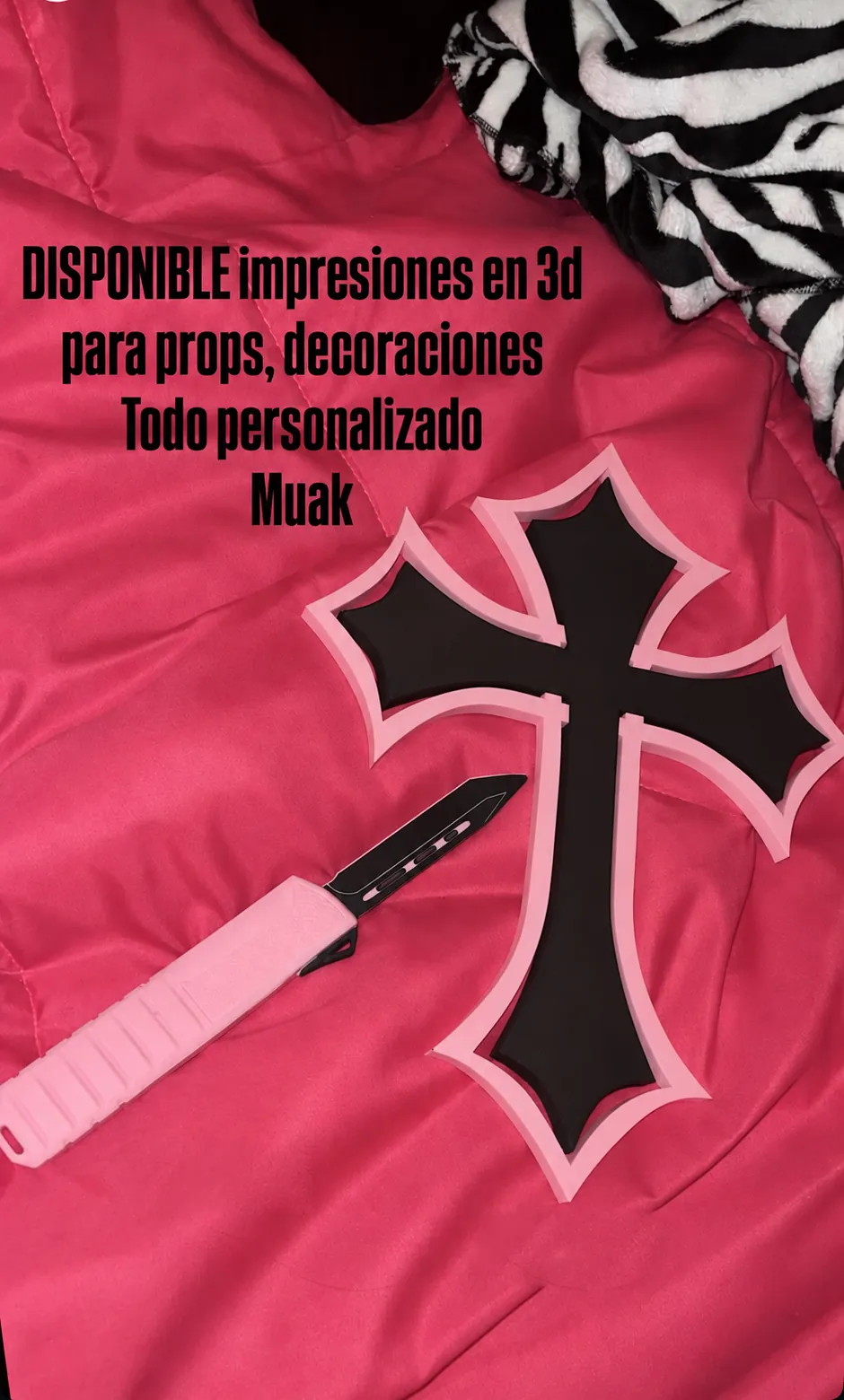 Cruz negra con borde rosa y navaja rosa impresas en 3D sobre una prenda rosa, en una publicación de la marca Cápsula Ultravioleta