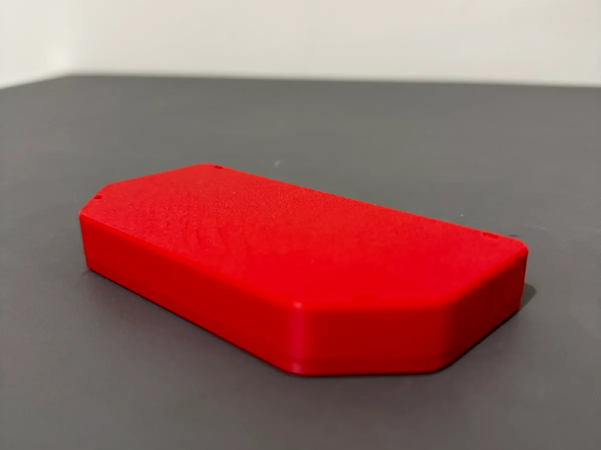Tapa roja impresa en 3D apoyada sobre una mesa gris